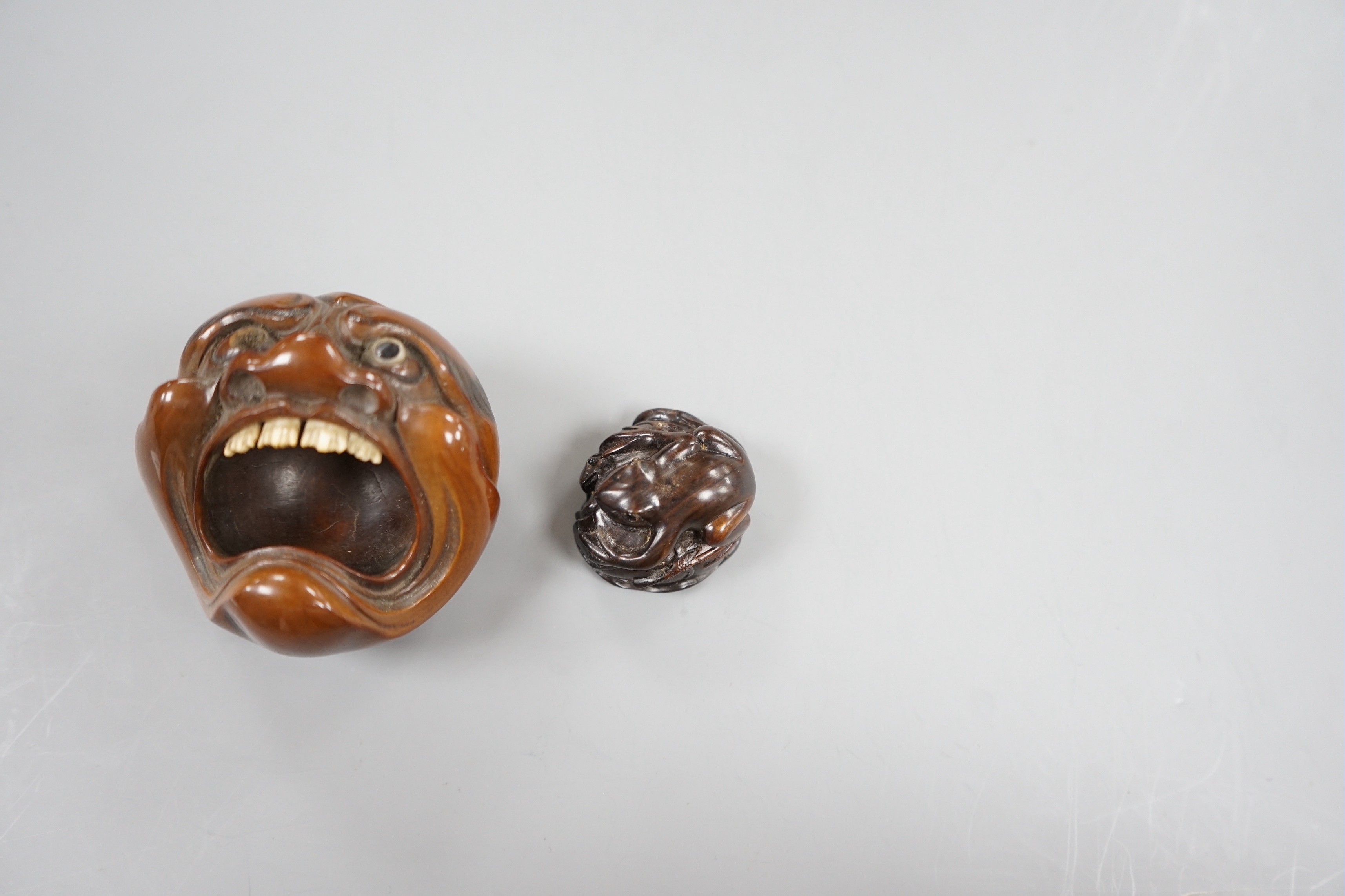 A Japanese mask nut carving wood carving, Meiji period and a netsuke of frogs, marks to bases, largest 7.5cm wide